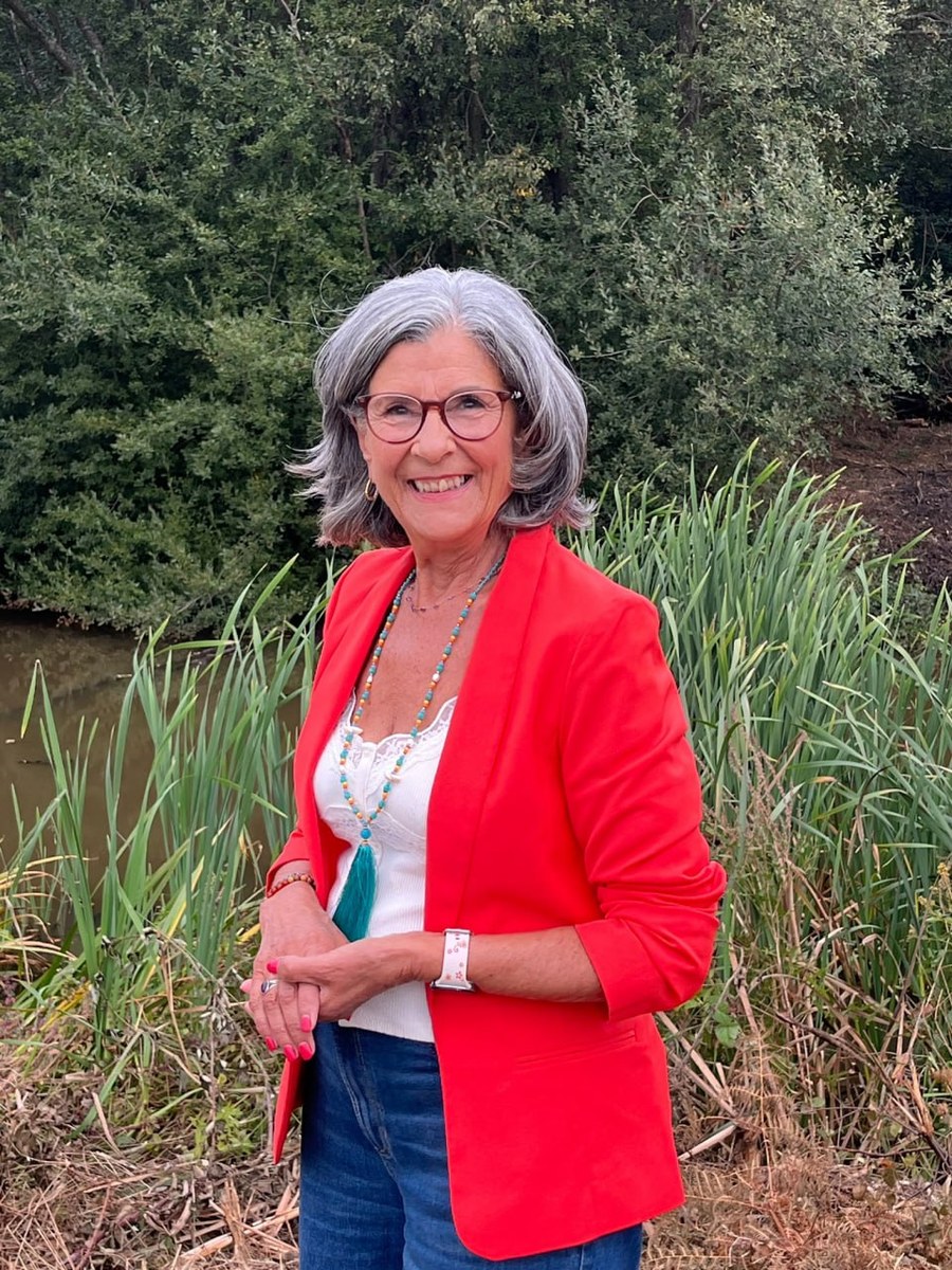 Sheela Hagan smiling in a red jacket beside a pond